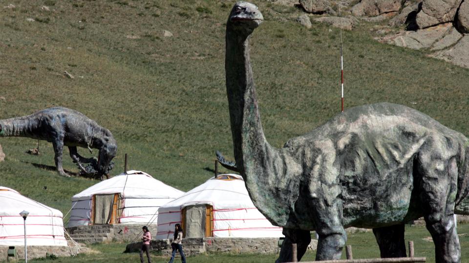 Visitors to a "ger" (tent) camp walk past large dinosaur sculptures used as a gimmick to promote the camp at the Terelj National Park near Ulan Bator, Mongolia. May 27, 2005. (File Photo /AP Archive)