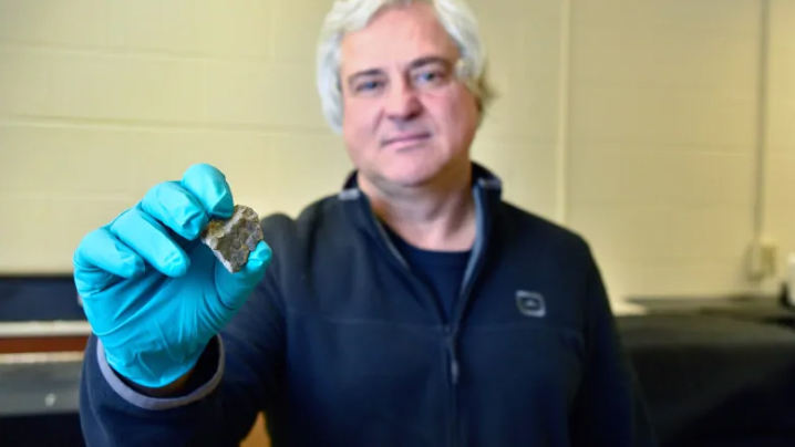University of Regina physics professor Mauricio Barbi shows off a piece of skin that belongs to a 72-million-year-old dinosaur. He was part of the team that found the preserved tissue on a dig. Researchers are looking into how this skin is connected to modern animals. (University of Regina Photography Dept)
